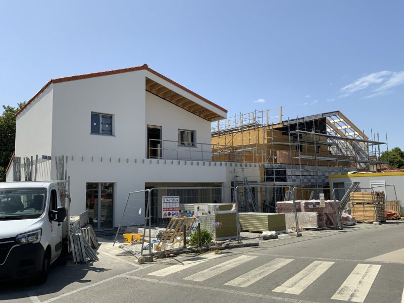 Maisons mitoyennes en construction, façades blanches avec toiture rouge, échafaudages, chantier actif