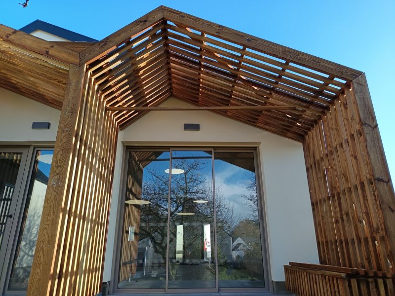Pergola contemporaine en bois avec lamelles horizontales, façade moderne avec bardage bois et grandes baies vitrées