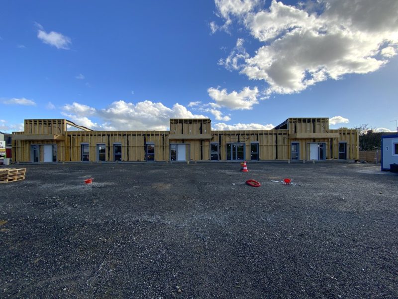 Construction de bâtiments commerciaux à ossature bois en cours, structure apparente avec ouvertures fenêtres et portes