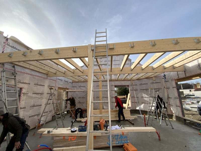 Chantier de construction bois avec ossature, poutres apparentes et isolation Rothoblaas en cours d'installation