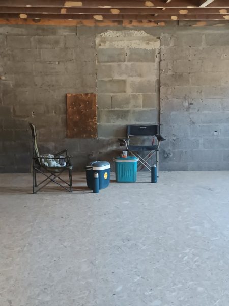 Intérieur de bâtiment en construction avec murs en blocs de béton brut, dalles apparentes et mobilier de chantier