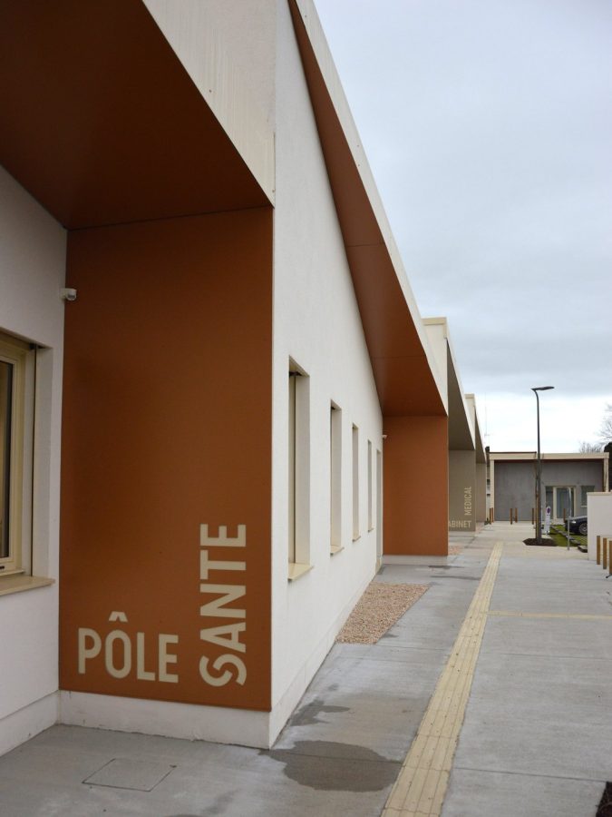 Façade moderne du Pôle Santé avec revêtement blanc et brun, auvent en bois et signalétique intégrée