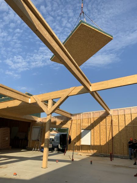 Assemblage de poutrelles en bois lamellé-collé sur chantier, panneau préfabriqué suspendu par grue