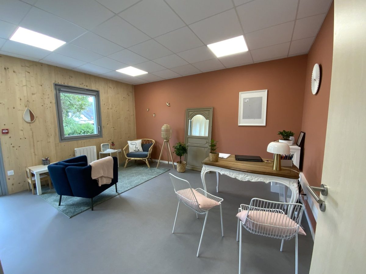 Bureau professionnel moderne avec mur terre cuite, plafond acoustique blanc et parquet bois naturel. Ameublement contemporain.