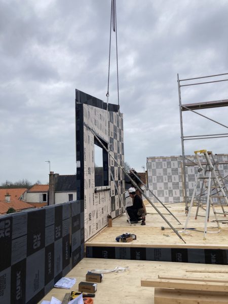 Levage d'un panneau préfabriqué en bois sur chantier de construction d'une extension contemporaine