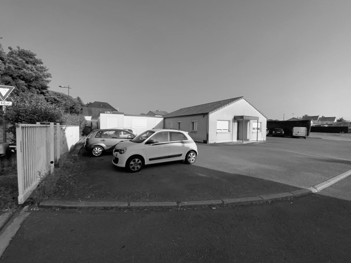 Maison individuelle plain-pied blanche avec toiture en tuiles, parking devant, zone résidentielle