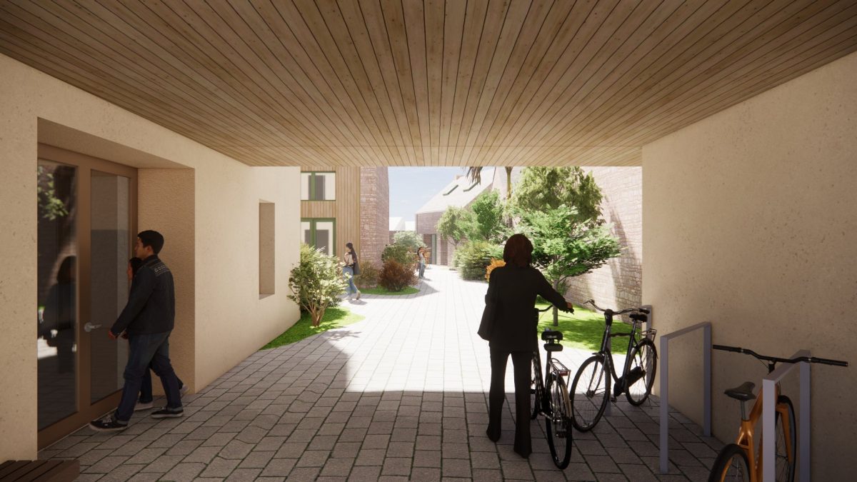 Passage couvert avec plafond bois lamellé, murs clairs, vélos garés, vue sur jardin commun et bâtiments en brique