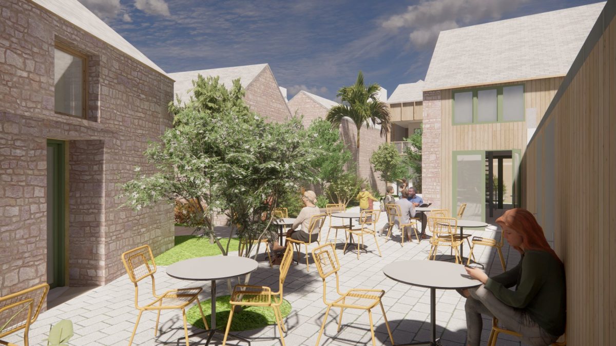 Cour intérieure avec terrasse en pavés, mobilier jaune, bâtiments en pierre et bois, végétation