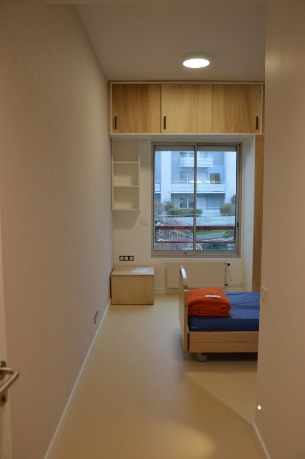 Chambre compacte avec mobilier en bois clair, lit avec couvertures colorées, bureau intégré et rangements muraux sur mesure