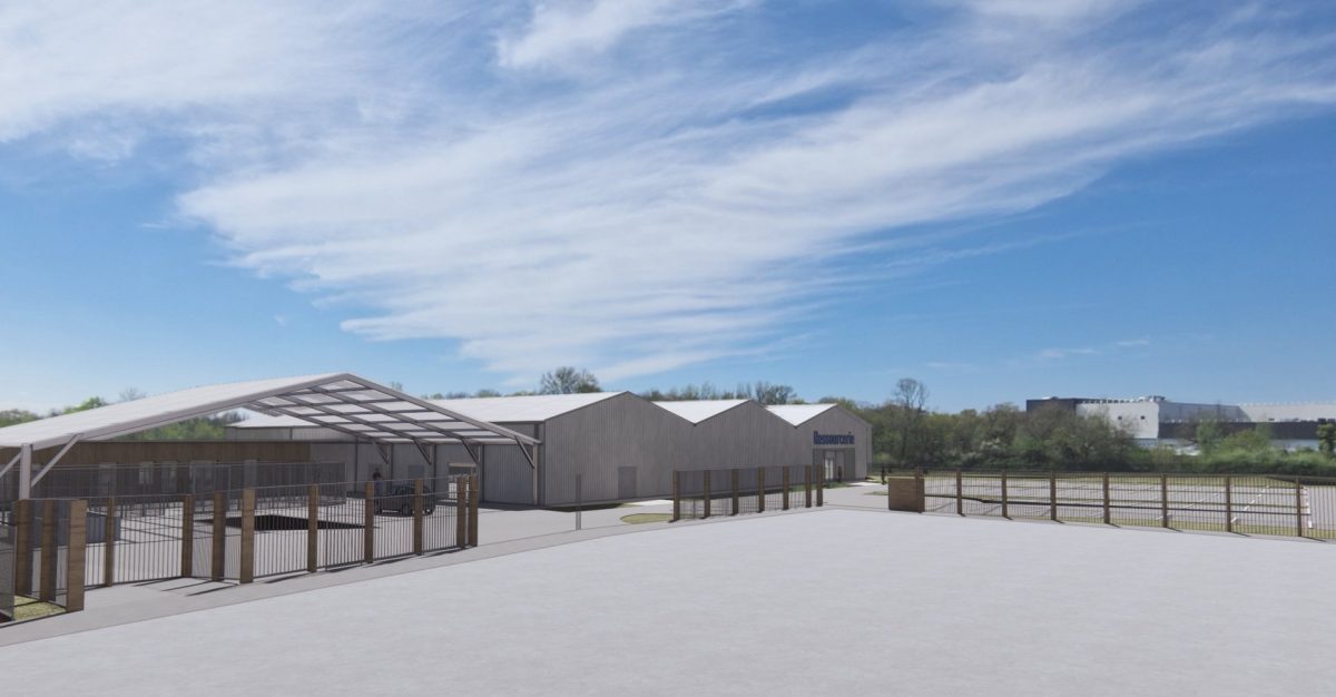 Bâtiment industriel moderne avec toiture métallique blanche, clôture en bois et portail d'entrée sous ciel bleu