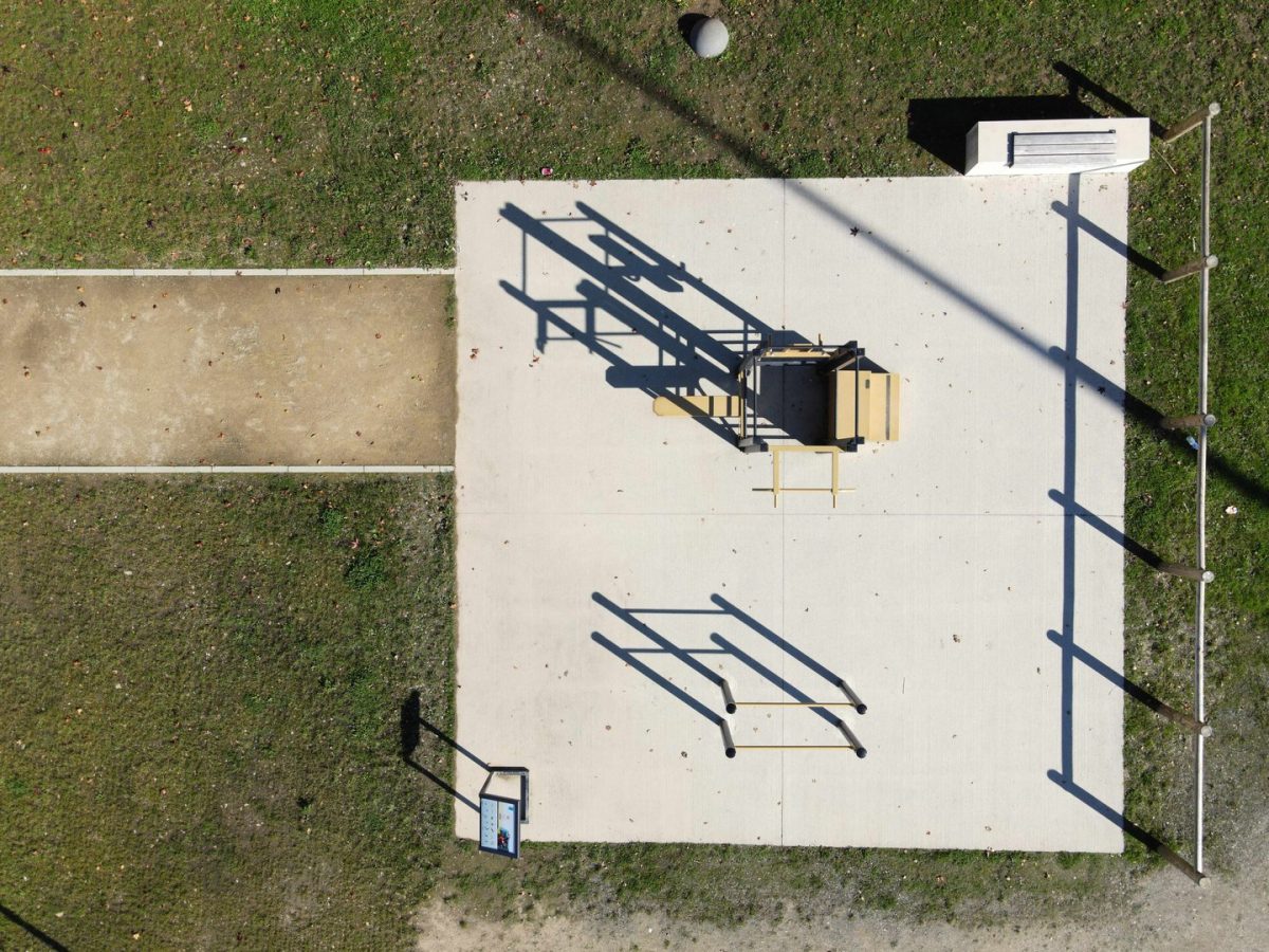 Vue aérienne d'une dalle de béton avec équipements extérieurs : banc, rampe d'accès et structure métallique centrale