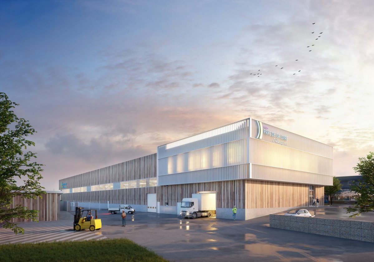 Bâtiment industriel moderne en bardage métallique avec quais de chargement, camions et personnel au crépuscule