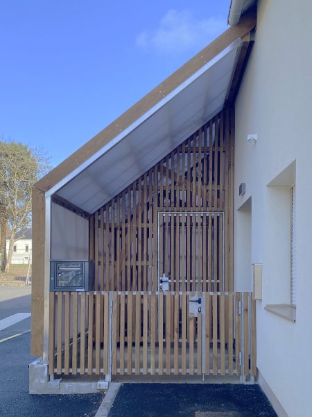 Maison contemporaine avec façade en claire-voie bois et bardage blanc sous ciel bleu