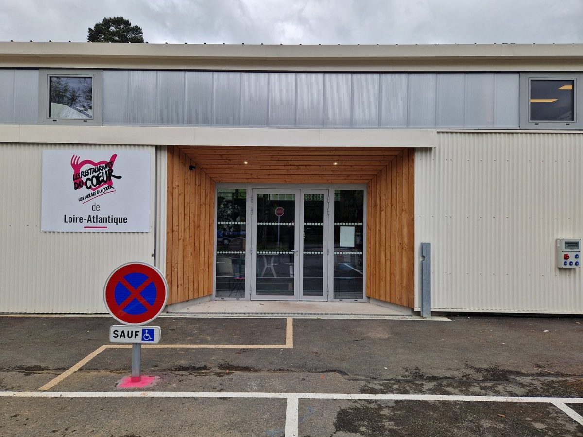 Façade de restaurant en tôle ondulée beige avec entrée en bois, enseigne Rétribuez du Coeur Loire-Atlantique