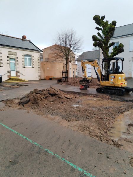 Chantier de rénovation avec mini-pelle devant maisons blanches, excavation en cours dans cour résidentielle
