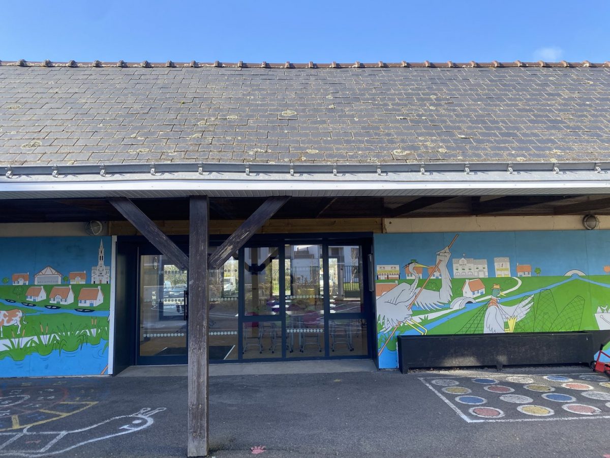 Entrée d'école maternelle avec fresque murale colorée, toit en ardoise et structure à poteaux en bois