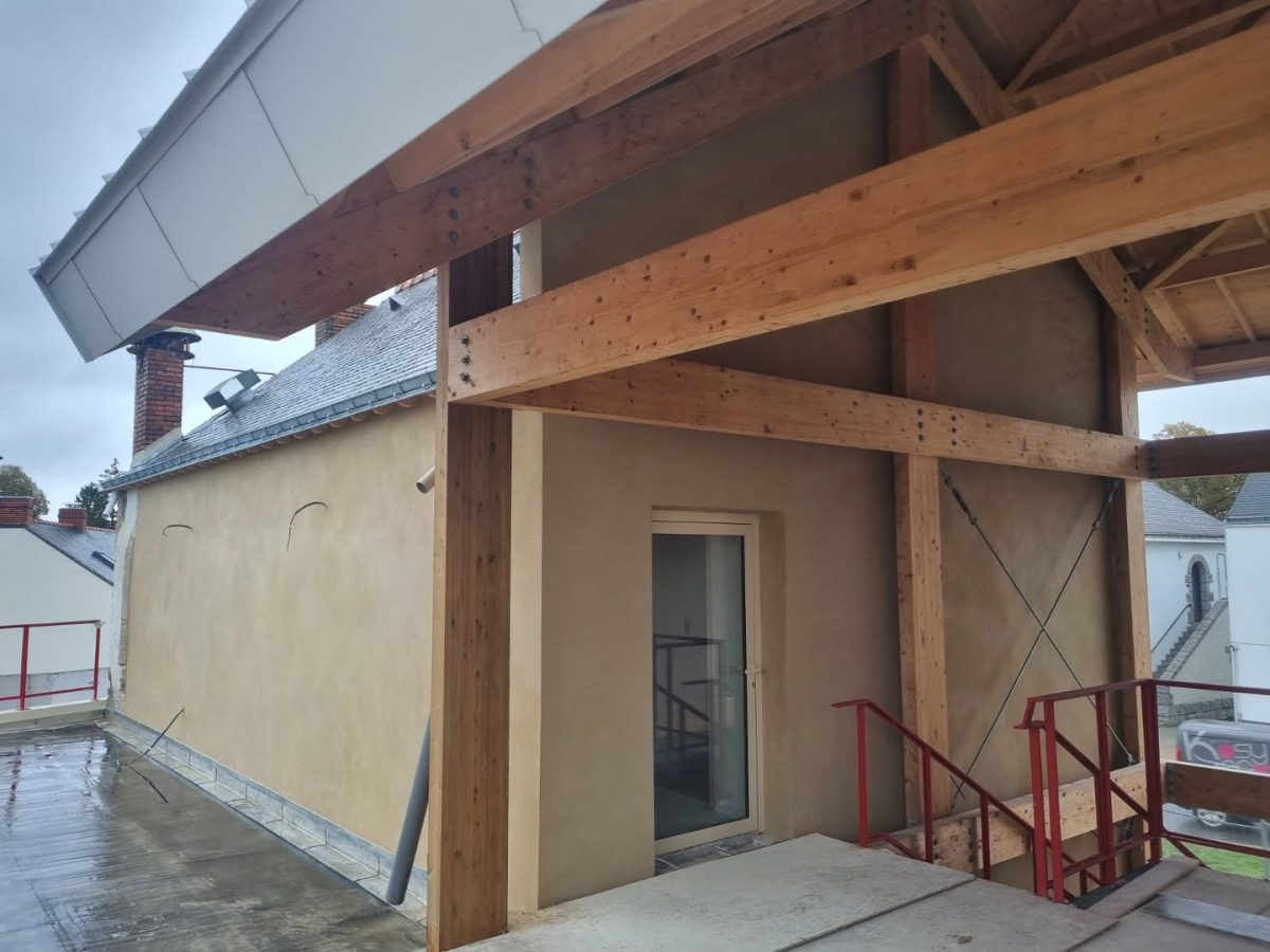 Construction d'une extension moderne en bois avec structure apparente, poutres en lamellé-collé et murs beiges