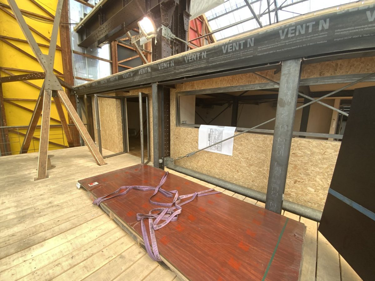 Chantier en cours avec structure acier, panneaux OSB, poutre marquée 'VENT N' et coffrages bois sur plancher