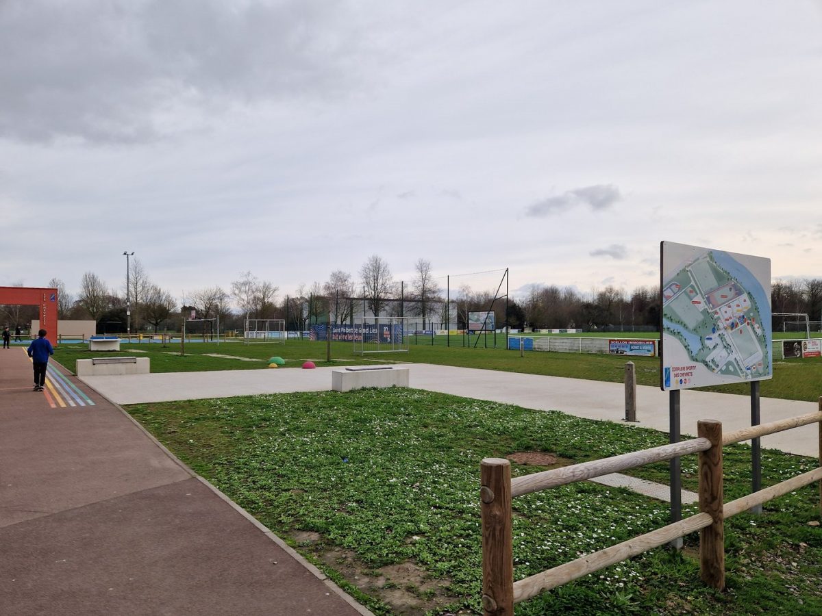 Terrain de sport multisports avec parcours skate, aires de jeux et panneaux d'information dans un parc communal
