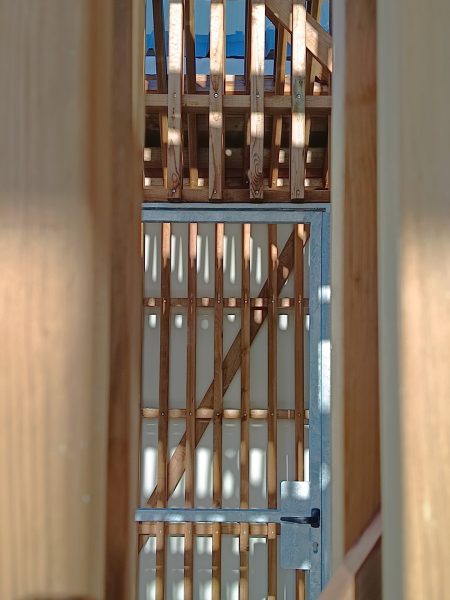 Porte intérieure avec cadre métallique et panneau en bois à lamelles verticales, détail architectural d'intérieur