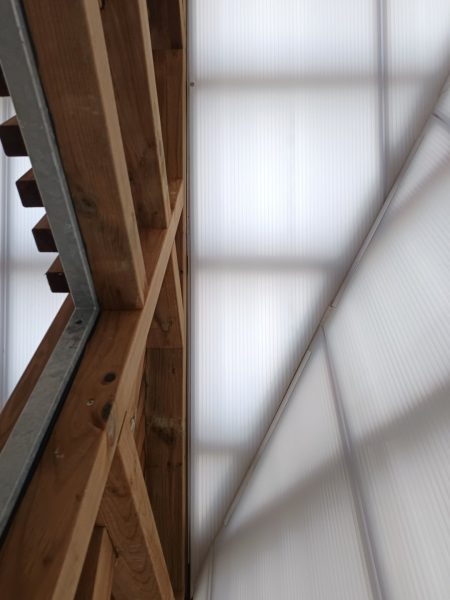 Détail de la charpente en bois avec panneaux isolants translucides formant le toit d'une structure moderne