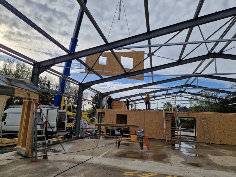 Construction d'une structure bois et acier avec ossature métallique apparente et panneaux OSB sur chantier