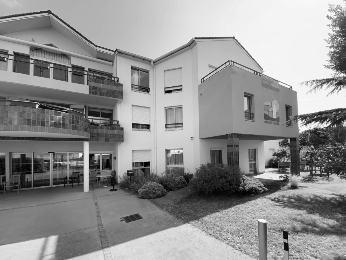 Immeuble résidentiel moderne en crépi blanc avec balcons, volets roulants et espaces verts paysagers