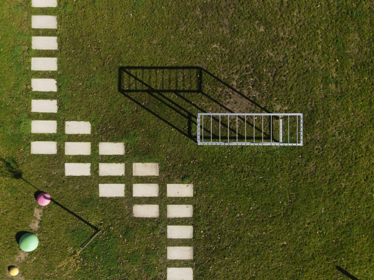 Vue aérienne d'une installation temporaire sur pelouse avec pavés blancs disposés en motif géométrique et échelles métalliques