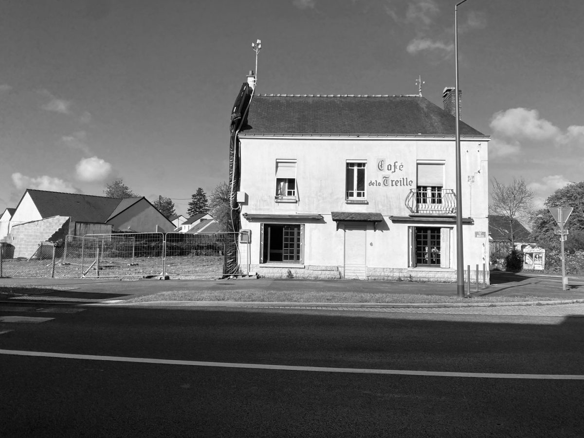 Café de la Treille, bâtiment blanc à deux étages avec balcon, volets et enseigne peinte, en contexte rural français