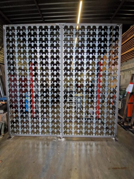 Panneau perforé décoratif en métal blanc avec silhouettes humaines colorées en atelier de fabrication industriel