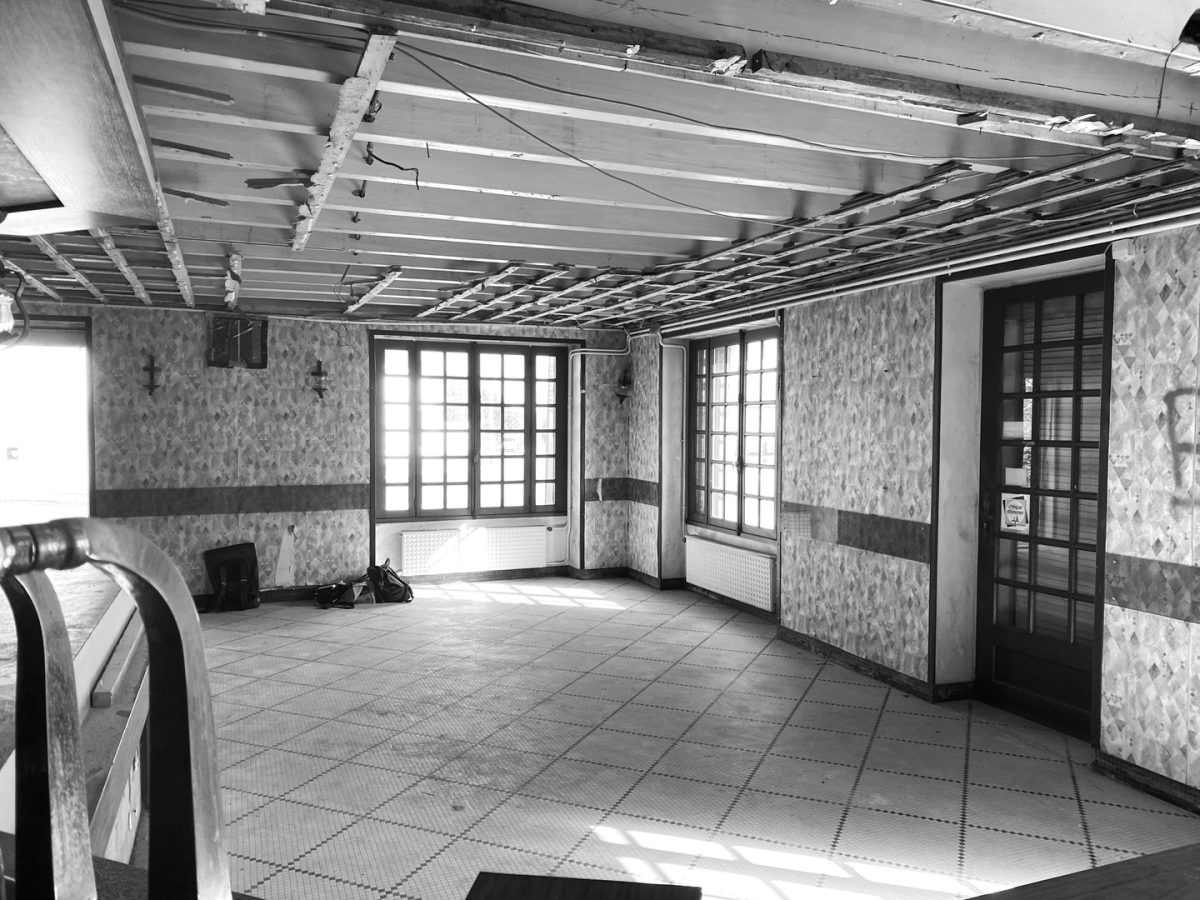 Espace intérieur en rénovation avec plafond apparent, carrelage au sol, papier peint floral et baies vitrées à carreaux