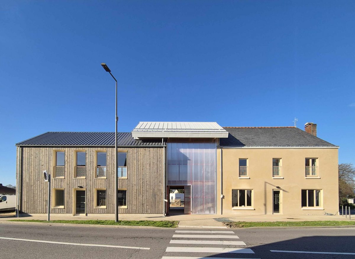 Rénovation d'un bâtiment en pierre enduite avec extension bois contemporaine, façade principale depuis la rue