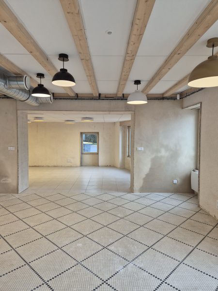 intérieur du bar, mur en enduit chaux chanvre, carrelage existant et poutres apparentes, les lumières sont allumées